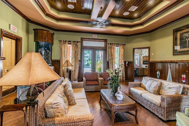 living room with wood-type flooring, ornamental molding, ceiling fan, a tray ceiling, and french doors