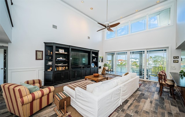 living area featuring a decorative wall, a wainscoted wall, dark wood-type flooring, visible vents, and a ceiling fan