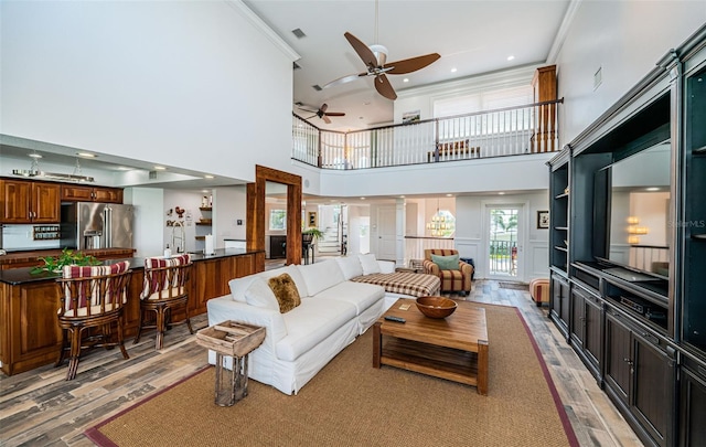 living area featuring ornate columns, ceiling fan, ornamental molding, and wood finished floors