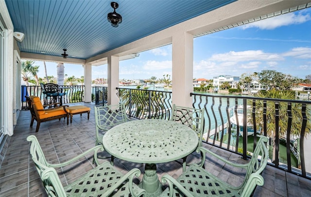 balcony with a water view, outdoor dining area, and a ceiling fan