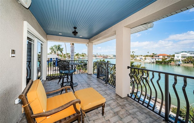 balcony with a water view and a ceiling fan