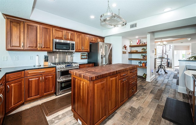 kitchen with visible vents, appliances with stainless steel finishes, a kitchen island, wood counters, and wood finished floors