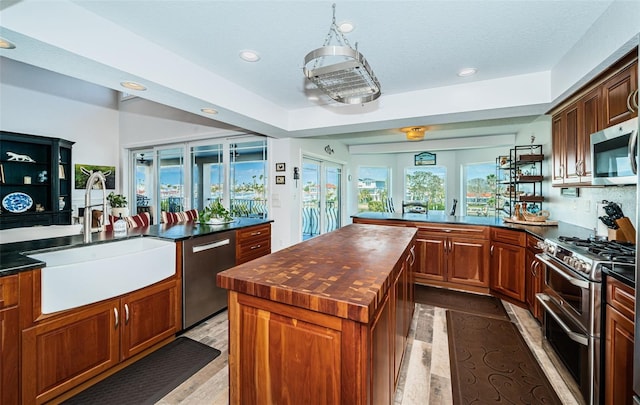 kitchen with recessed lighting, stainless steel appliances, a sink, light wood-type flooring, and a center island