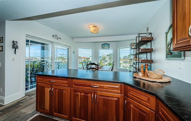 kitchen featuring dark countertops, brown cabinetry, baseboards, and dark wood finished floors