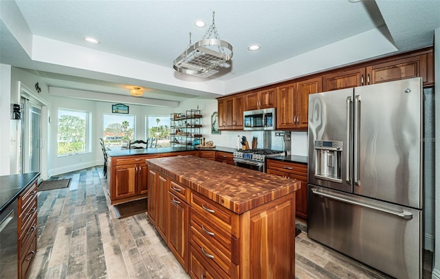 kitchen with a peninsula, premium appliances, dark countertops, and a kitchen island