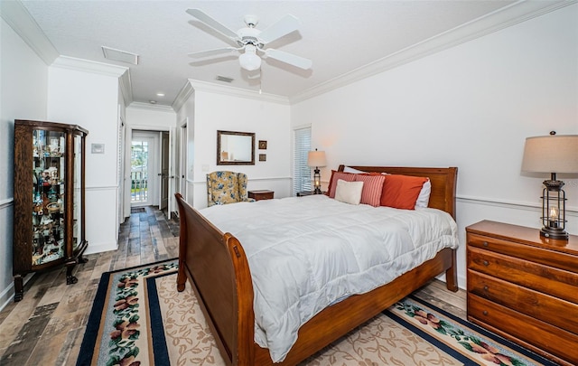 bedroom with light wood-type flooring, ceiling fan, visible vents, and ornamental molding