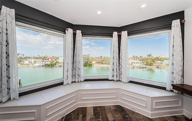 room details featuring a water view, a decorative wall, and wood finished floors