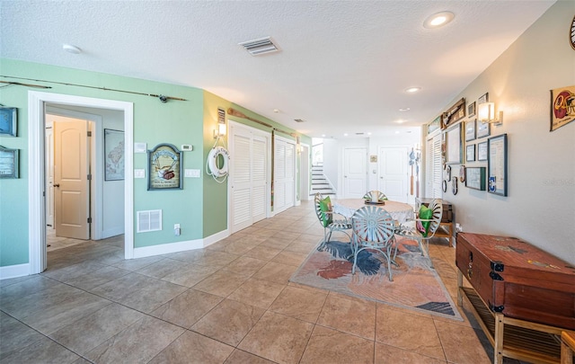 dining space featuring visible vents, a textured ceiling, and light tile patterned floors