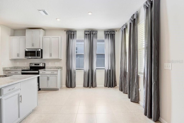 kitchen featuring appliances with stainless steel finishes, light tile patterned floors, and light stone counters