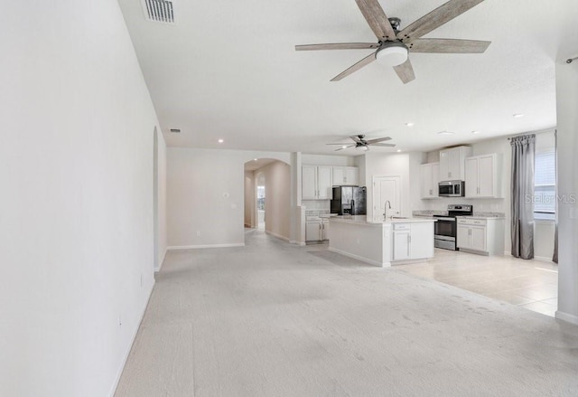 unfurnished living room with sink, light colored carpet, and ceiling fan