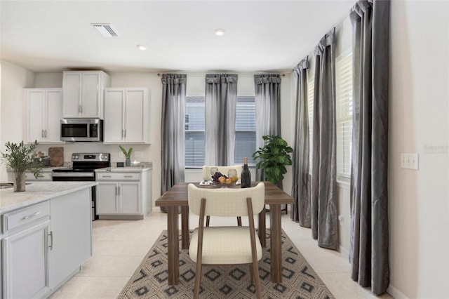 6307 113th Ter E, Parrish, FL 34219 - kitchen with appliances with stainless steel finishes, plenty of natural light, white cabinets, and light tile patterned flooring