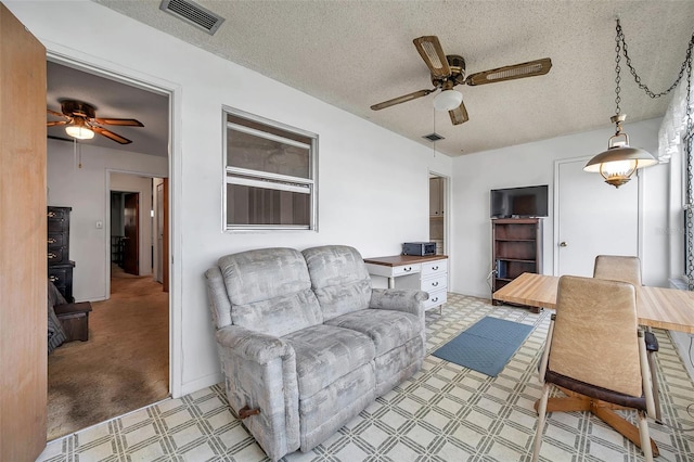 living room with ceiling fan and a textured ceiling