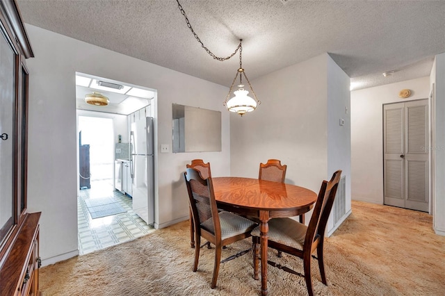 carpeted dining room featuring a textured ceiling