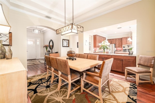 dining room with a raised ceiling, light hardwood / wood-style flooring, and crown molding