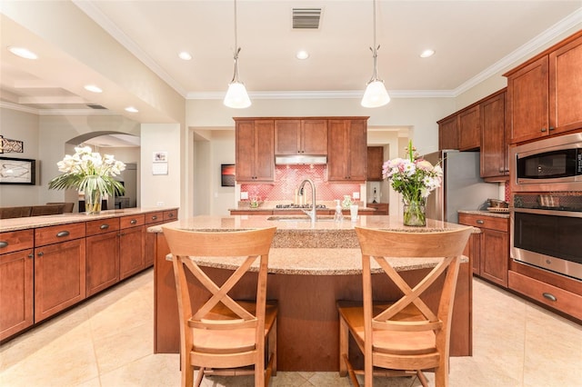 kitchen featuring a breakfast bar area, stainless steel appliances, and decorative light fixtures