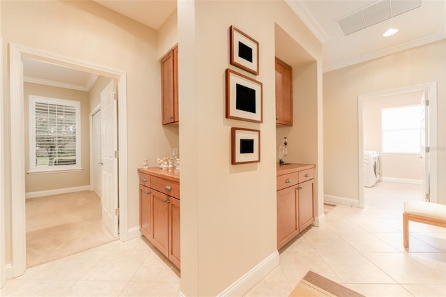 hallway featuring light tile patterned floors, washer / dryer, and ornamental molding