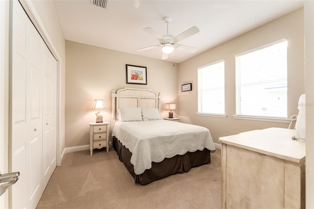 bedroom with ceiling fan, light carpet, and a closet