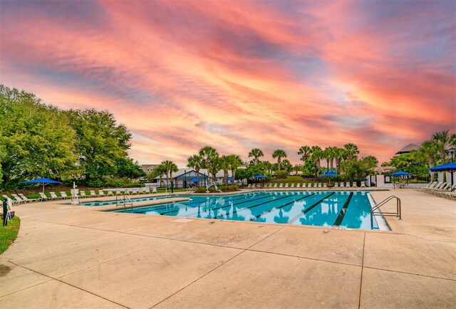 pool at dusk featuring a patio area