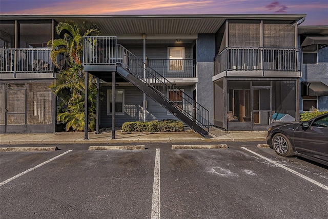 property at dusk with uncovered parking and stairway