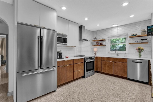 kitchen with wall chimney exhaust hood, appliances with stainless steel finishes, sink, and tasteful backsplash