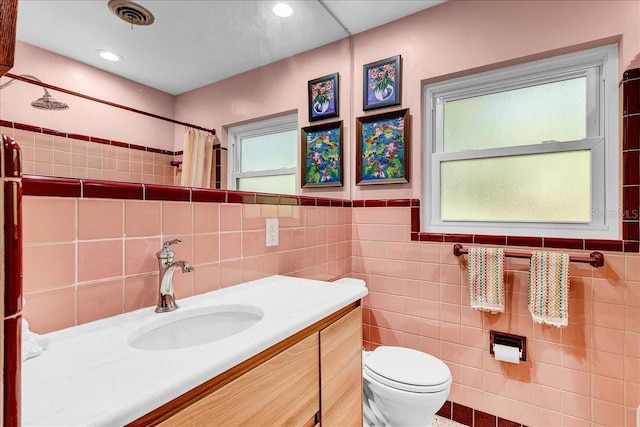 bathroom with vanity, toilet, a shower with shower curtain, and tile walls