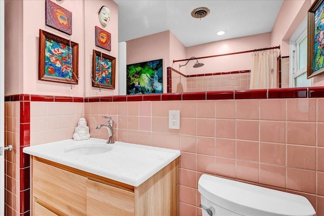 bathroom featuring walk in shower, vanity, toilet, and tile walls