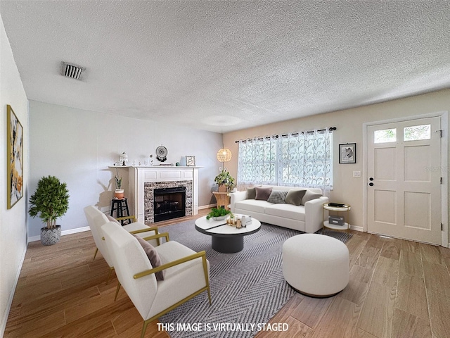 living room featuring visible vents, a fireplace, baseboards, and wood finished floors