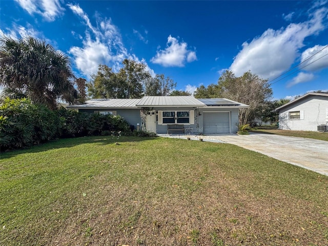 single story home featuring solar panels, concrete driveway, a front yard, metal roof, and a garage