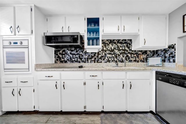 kitchen with sink, appliances with stainless steel finishes, light stone counters, white cabinets, and decorative backsplash