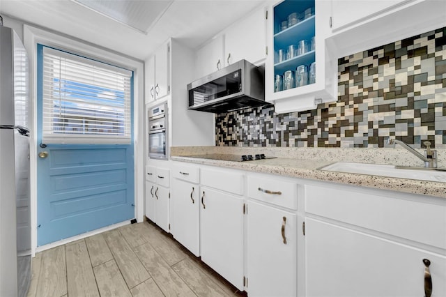 kitchen featuring tasteful backsplash, white cabinetry, sink, light hardwood / wood-style floors, and stainless steel appliances