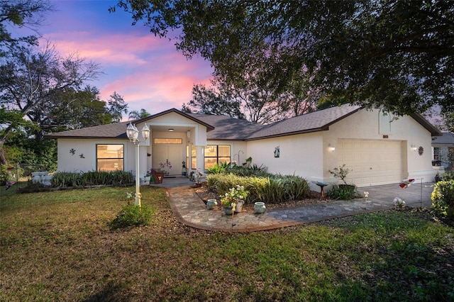 ranch-style house with a garage and a lawn