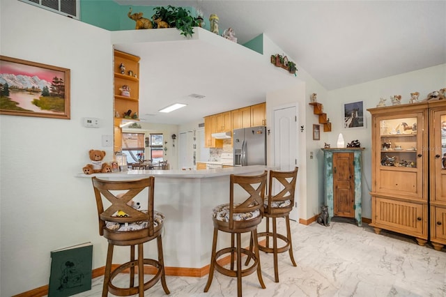 kitchen featuring stainless steel fridge with ice dispenser, kitchen peninsula, and a kitchen bar