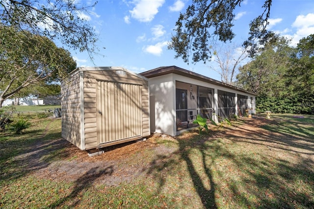 view of outdoor structure with a yard and a sunroom