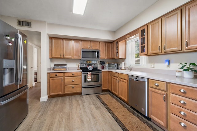 kitchen featuring appliances with stainless steel finishes, sink, and light wood-type flooring