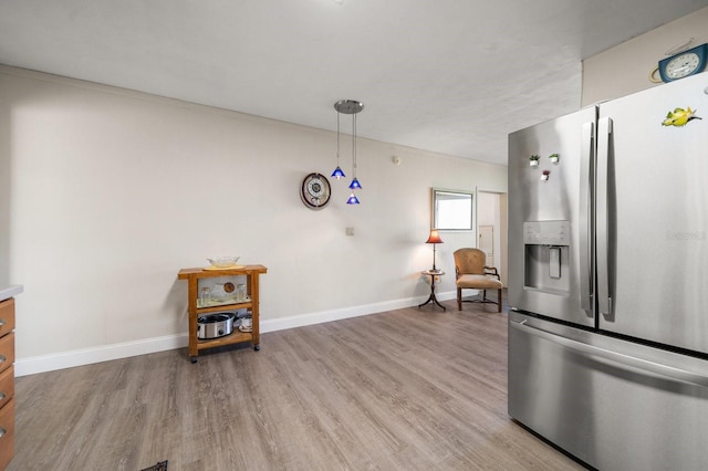 kitchen with decorative light fixtures, light hardwood / wood-style floors, and stainless steel refrigerator with ice dispenser