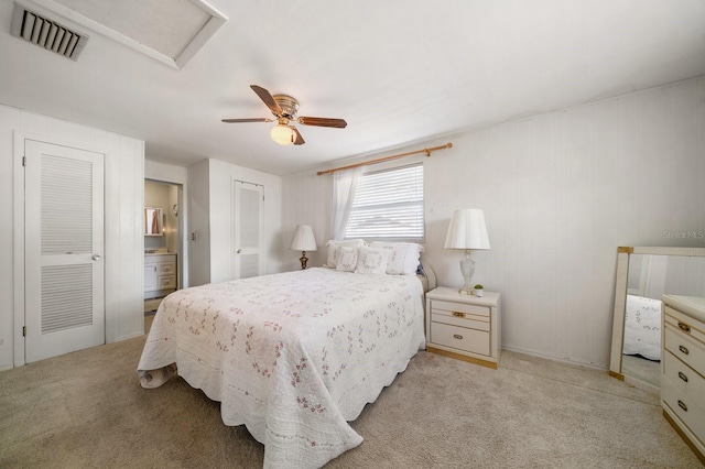 bedroom with connected bathroom, light carpet, and ceiling fan