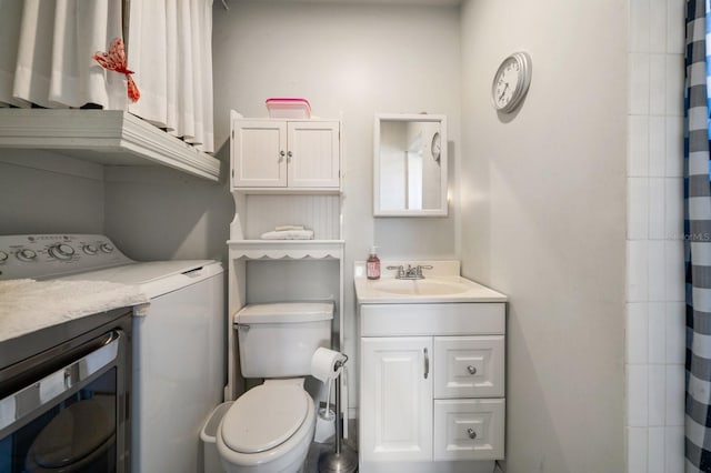 bathroom with vanity, toilet, and washer / dryer