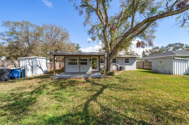 rear view of property featuring a wooden deck, a yard, central air condition unit, and a storage unit