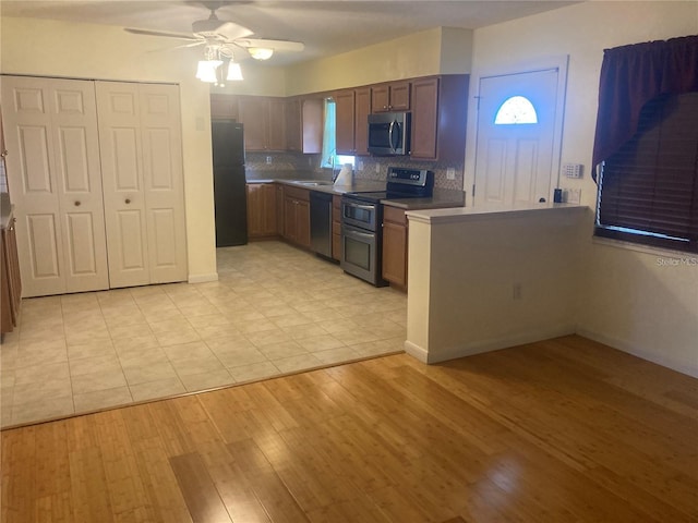 kitchen featuring sink, ceiling fan, appliances with stainless steel finishes, backsplash, and light hardwood / wood-style floors