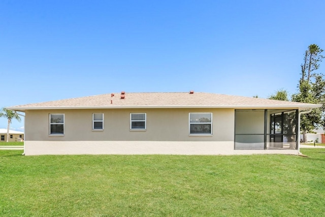 rear view of house featuring a sunroom and a lawn