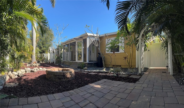 back of property featuring a sunroom and a fire pit