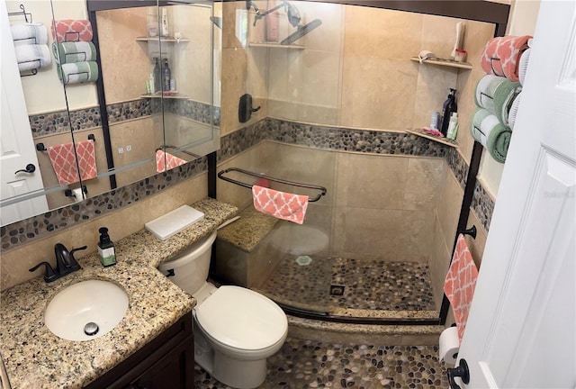 bathroom with toilet, an enclosed shower, tile walls, vanity, and backsplash