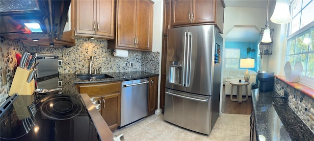 kitchen featuring pendant lighting, sink, dark stone countertops, backsplash, and stainless steel appliances