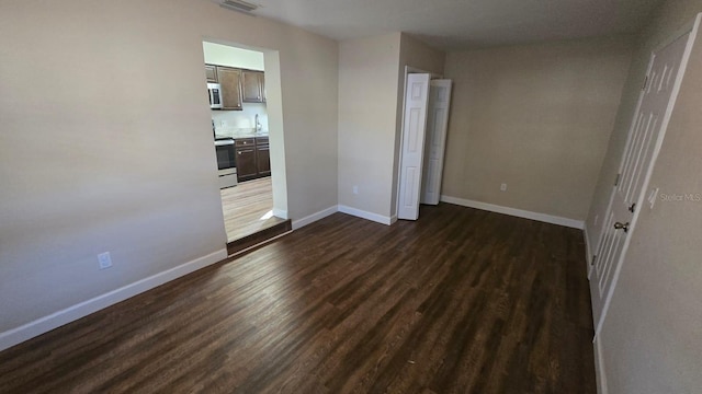 unfurnished bedroom with ensuite bathroom and dark hardwood / wood-style flooring