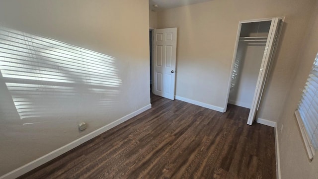 unfurnished bedroom with dark hardwood / wood-style flooring and a closet