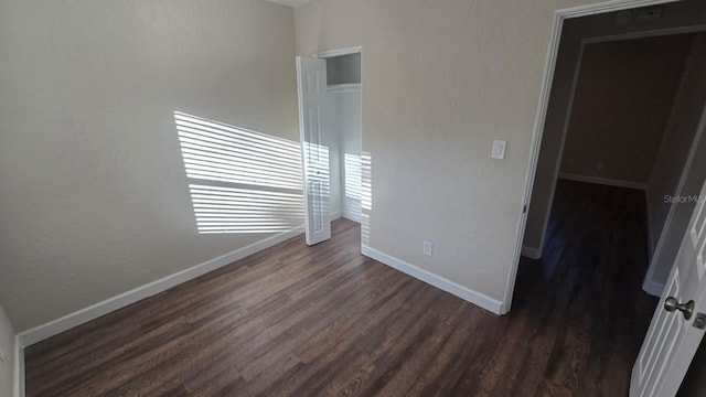 unfurnished bedroom with dark wood-type flooring and a closet