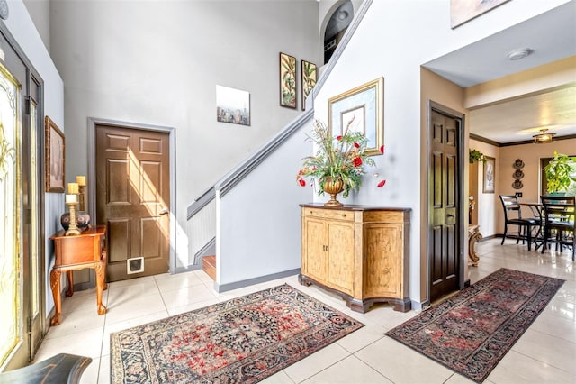 tiled entryway featuring a towering ceiling and ornamental molding