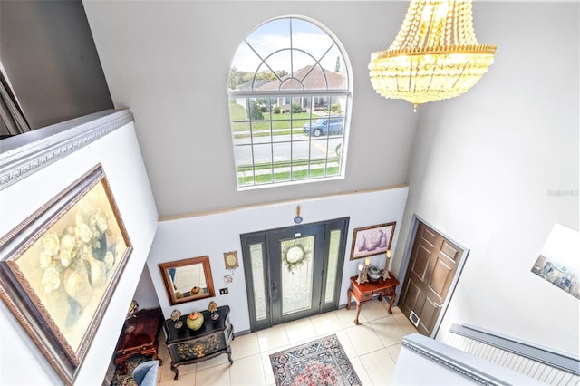 entryway with light tile patterned flooring, a towering ceiling, and a notable chandelier