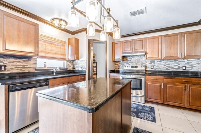 kitchen with sink, hanging light fixtures, stainless steel appliances, ornamental molding, and a kitchen island