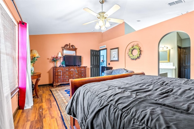 bedroom with hardwood / wood-style flooring, ceiling fan, ensuite bathroom, and vaulted ceiling